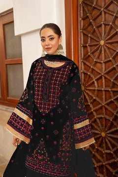 Woman wearing a black embroidered traditional outfit in an indoor setting.